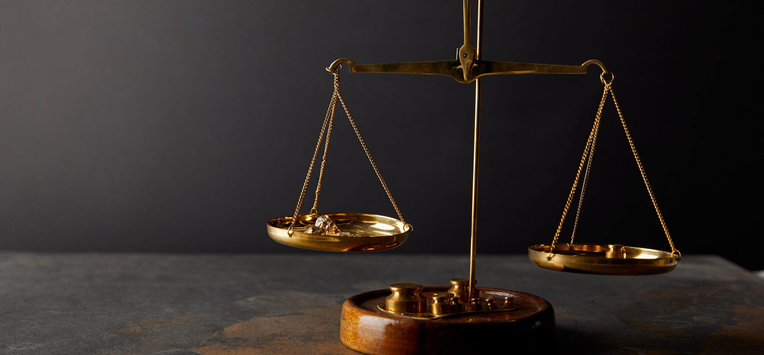 Evaluating the Integration of 3D Printing in Orthopaedic Practices A traditional balance scale with gold nuggets in one pan, set against a dark background.