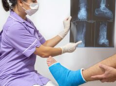 Fundamentals of Fracture Management A healthcare professional examines a patient's foot X-ray while the patient's leg is in a cast.