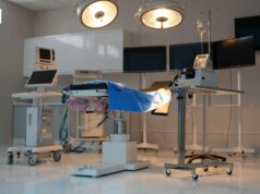 Impact of Technological Advancements on Total Hip and Knee Arthroplasty A modern, well-equipped operating room with surgical lights, an operating table covered in blue drapes, and various medical monitors and equipment.