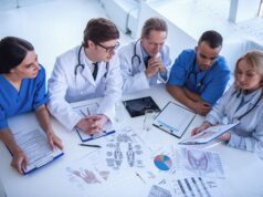Reducing Costs, Improving Care: Financial Strategies for Orthopaedic Surgeons A group of medical professionals, including doctors and nurses, are gathered around a table reviewing medical charts and anatomical diagrams during a meeting or conference.