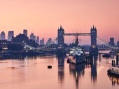 Innovate and Connect: Surgeons Congress 2024 Comes to London This image captures a serene view of London's Tower Bridge at dawn, with the city skyline and a moored ship reflecting on the calm waters of the Thames.